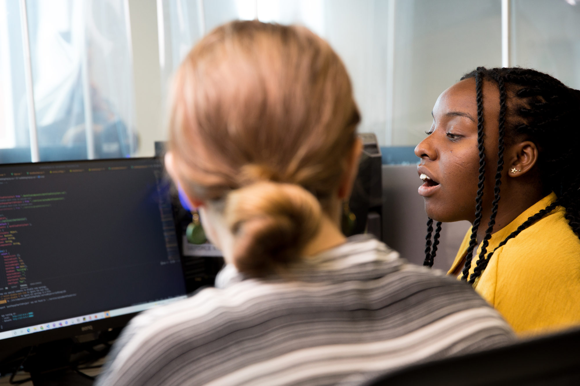 Two female coders working on a data analysis project.