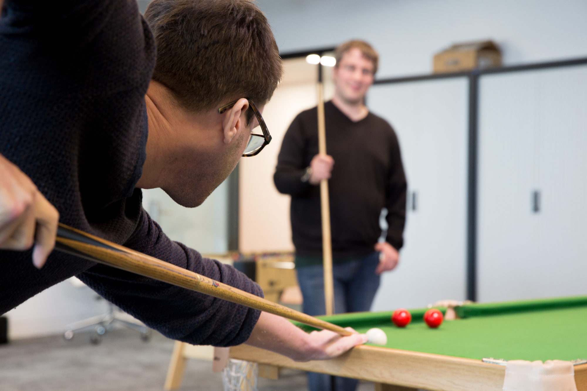 Two Slingshot Simulations employees playing a game of pool.