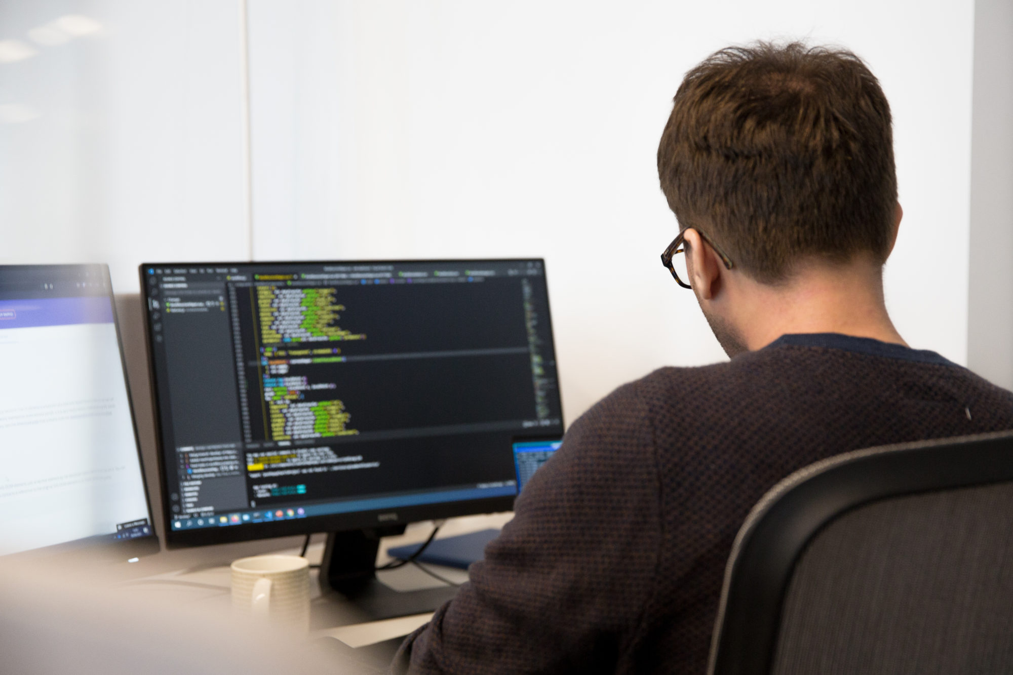 A digital twin company coder working at a computer with code on the screen.