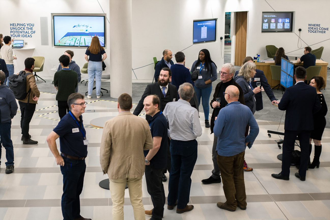A group of Slingshot Simulations employees at a software event chatting.