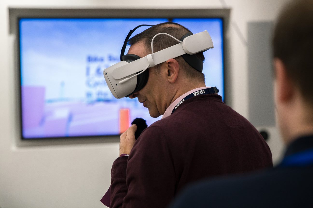 A male wearing a VR headset and smiling.